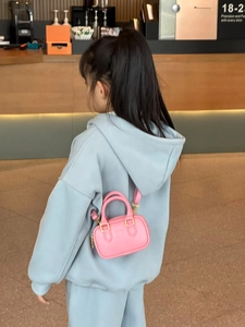 Kleinkind im hellblauen Hoodie mit einer rosa Mini-Umhängetasche mit Goldbeschlägen