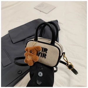 Close-up of cream canvas tote with RIR embroidery and cute brown plush bear charm