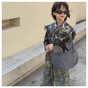 Close-up of grey waterproof nylon crossbody bag with wide shoulder strap on a child