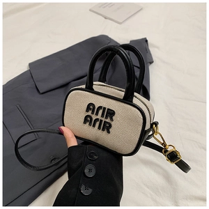 Detail of canvas mini handbag with black leather trim and Arir Arir embroidery text