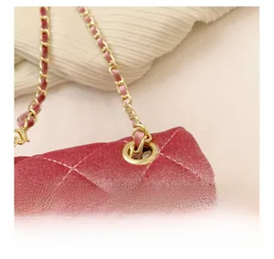 Gros plan sur la texture velours rose matelassé et la chaîne dorée du sac bandoulière