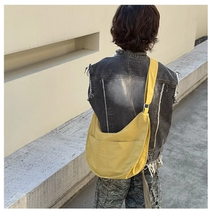 Outdoor shot of a bright yellow crescent crossbody bag styled with casual outfits