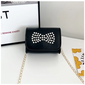 Detail of black mini crossbody bag with pearl bow design and golden chain strap for girls
