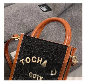 Detailed close-up of mini crossbody bag with orange leather trim and TOCHA CUTE embroidery