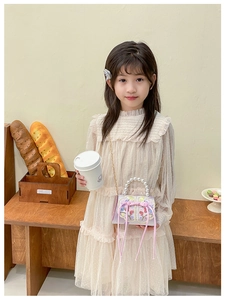 Détail du sac à main violet brodé pour fille avec poignée en perles et nœud sur une robe