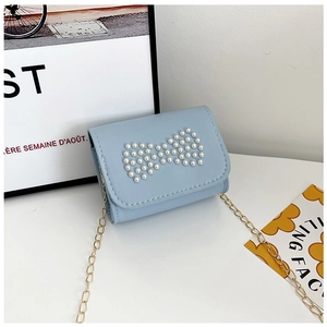 Detailed macro view of the light blue crossbody bag with pearl bow and golden chain strap