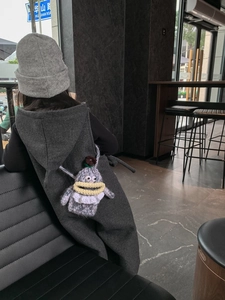 Detail showing a grey crochet monster bag with funny lips worn by a child in daily life