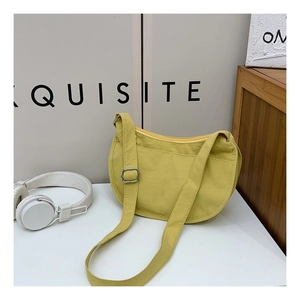 Close-up of bright yellow half-moon crossbody bag with textured fabric and zip closure