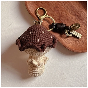 Gros plan du pendentif champignon crocheté main avec plaque en métal sur plateau