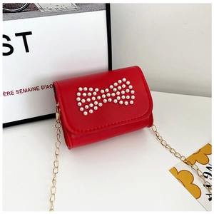 Close-up of red mini handbag for girls with pearl bow ornament and gold chain strap