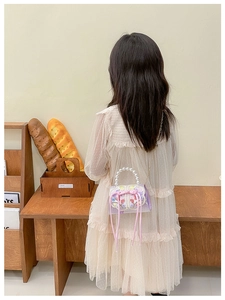 Détail d'un sac à main brodé pour filles avec poignée en perles et nœud en ruban rose