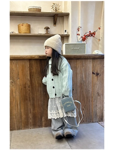 Kid outfit detail featuring light green cable knit cardigan and blue mini crossbody bag