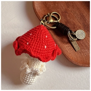 Détail d'un porte-clés champignon rouge au crochet avec anneau en bronze et étiquettes