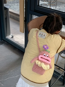 Detailed view of hand-knitted pink monster bag with 3D floral accents on a child vest