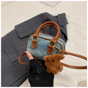 Detaillierte Makroansicht der hellblauen Denim-Handtasche mit braunem Lederbesatz und Griff