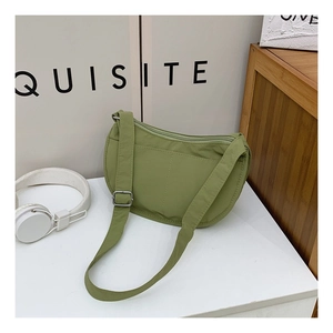 Detail of avocado green nylon crescent bag featuring adjustable strap and silver buckles