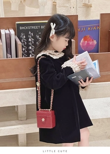 Close-up of a child wearing a red quilted mini box bag with gold chain strap detail