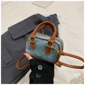 Detailaufnahme einer Mini-Bowlingtasche aus blauem Denim mit braunen Ledergriffen