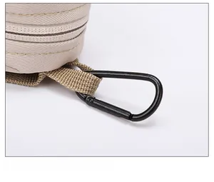 Detail of sturdy black metal carabiner clip and nylon webbing on beige mini pouch