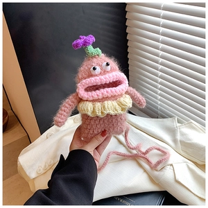 Detail of pink hand-knitted monster bag featuring big eyes and thick lips crossbody strap