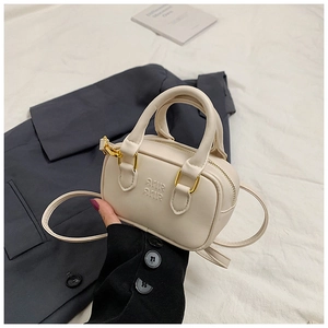 Nahaufnahme der cremefarbenen Mini-Bowlingtasche mit Logo-Prägung und Golddetails