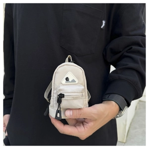 Detail of beige mini nylon coin pouch showing hiking mountain logo and zipper pulls