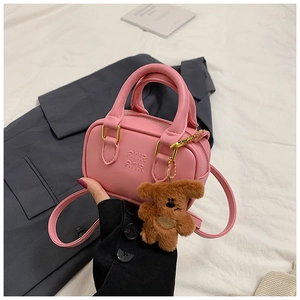 Rosa Mini-Ledertasche mit AMIR-Prägung und braunem Plüschbär-Anhänger im Detail