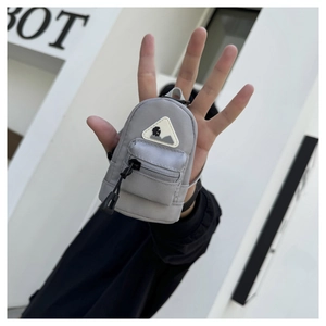 Close-up of a grey mini tactical backpack charm with zipper details held in hand
