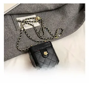 Detail of black quilted leather box bag featuring gold floral clasp and chain strap