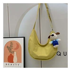 Detail of ginger yellow hobo bag with adjustable strap and cute plush puppy charm pendant