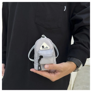 Close-up of light gray mini backpack coin purse with shoulder strap held in hand