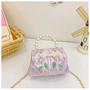 Détail du sac en satin lavande avec broderie florale et pendentif à franges perle