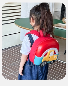 Detail of cartoon car hardshell backpack with red straps shown from a back view on a child