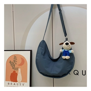 Detailed view of a blue crescent nylon crossbody bag with a cute puppy plush pendant
