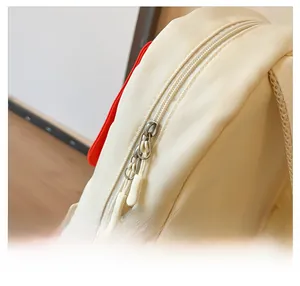 Detail view of smooth double metal zippers on kids cream house-shaped backpack
