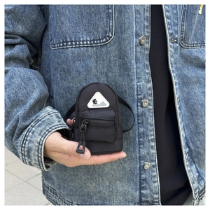 Miniature black nylon backpack style earphone case shown held in hand for scale