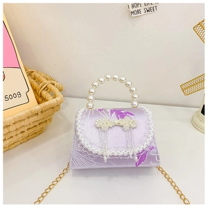 Détail de broderie florale sur sac en satin lilas avec poignée en perles et bordure dentelle