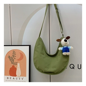 Detail of green hobo bag featuring nylon fabric and a cute plush dog pendant