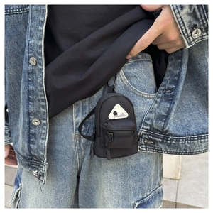 Mini black backpack keychain with metal hook shown attached to denim jeans for outdoor use