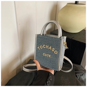 Close-up of mini blue denim square bag with silver trim and cute yellow embroidery