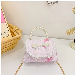 Détail du mini sac en jacquard rose avec poignée en perles, dentelle et nœud décoratif