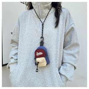Close-up of tricolor canvas neck pouch with dual zipper pockets and woven lanyard