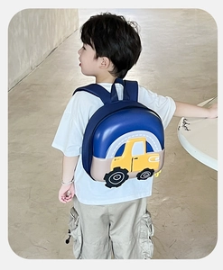 Side view of toddler wearing a 3D blue car hardshell backpack in a modern room setting