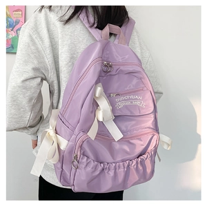 Dettaglio di uno zaino viola con fiocchi bianchi e design con tasche multiple