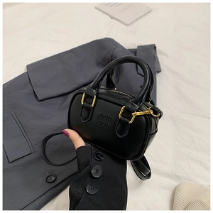 Detail einer schwarzen Mini-Boston-Tasche mit AIUR-Prägung und Goldbeschlägen