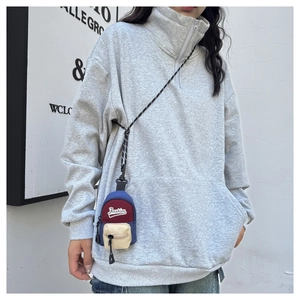 Close-up of a mini tricolor neck pouch with zipper detail on a grey sweater