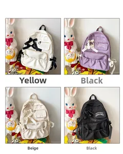 Dettaglio di zaini scolastici carini in bianco, viola, beige e nero con fiocchi decorativi