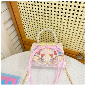 Gros plan du sac rose brodé pour fille avec poignée en perles et ruban à fleurs