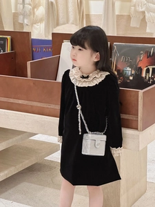 Close-up of a silver quilted chain box bag on a black velvet dress for children