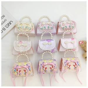 Détail de mini sacs avec broderie chinoise, poignée en perles et pompons en soie
